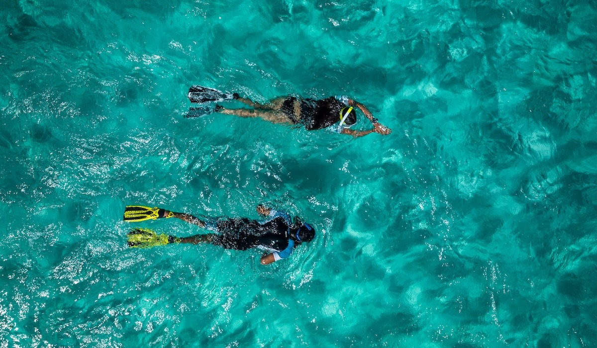 Snorkeling in mare cristallino con due persone che nuotano in superficie con maschera e pinne